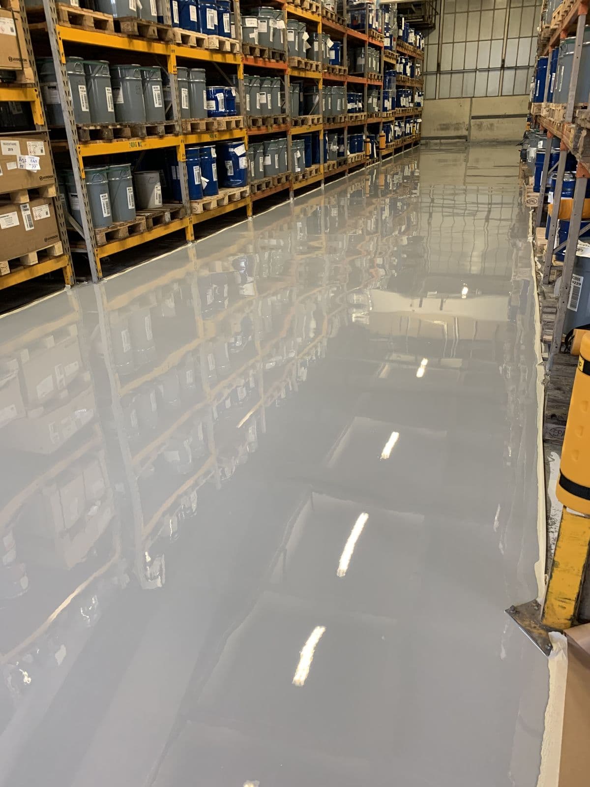 Glossy grey epoxy flooring in warehouse aisle