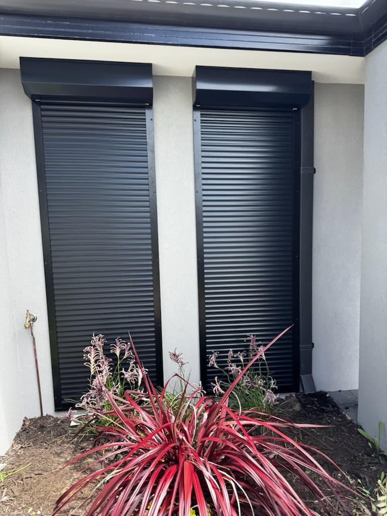 Pair of black roller shutters on residential home exterior